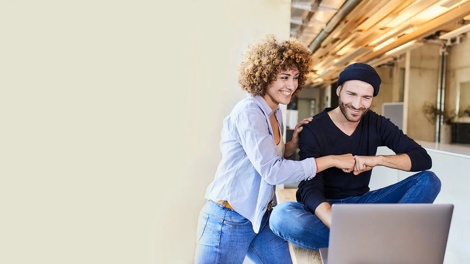 zwei Personen die vor einem Laptop in einem Büro sitzen 