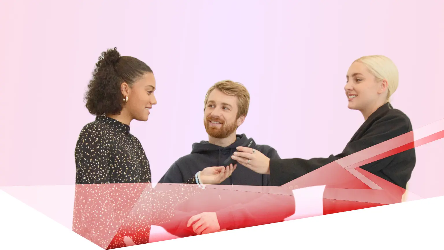 hree people engaged in conversation in front of a pink background with the text “Unlock a better tomorrow” and red double arrows.