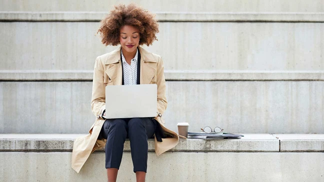 Frau sitzt auf Stufen mit Laptop