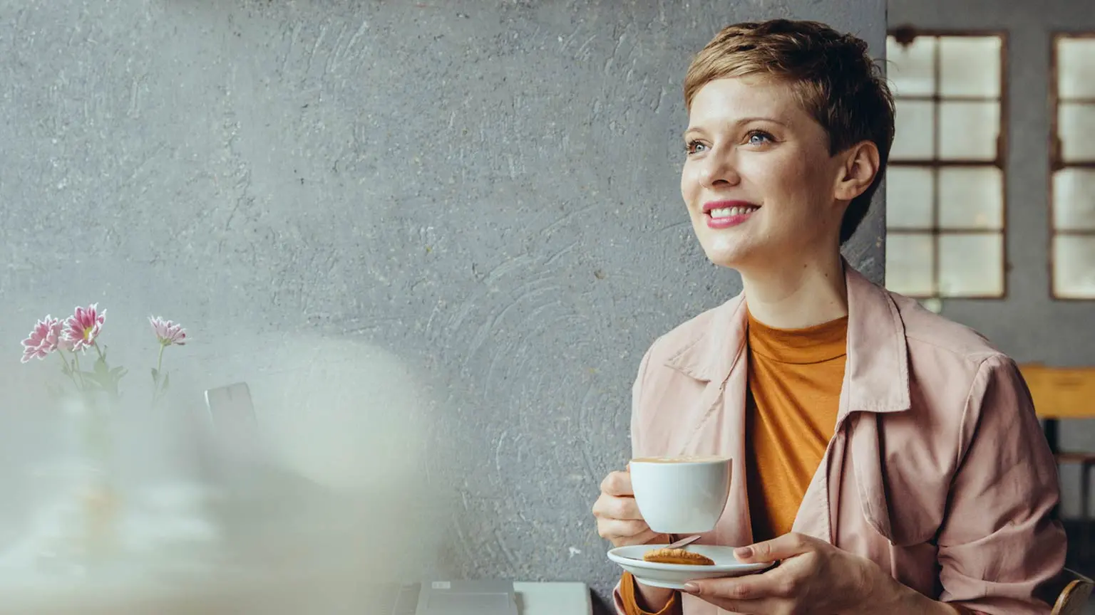 Frau mit Kaffeetasse blickt aus dem Fenster