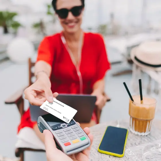 Frau sitzt im Cafe und bezahlt mit Visa Debit Card