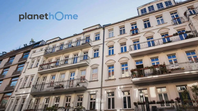 Helle Hausfassade mit Balkonen bei blauem Himmel, oben links das Logo planetHome Immobilien.