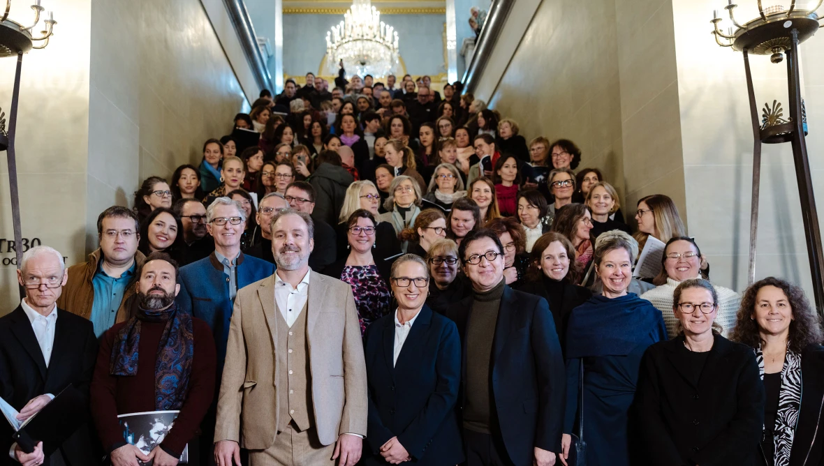 Eine große Gruppe von Personen steht auf einer Treppe, die bis zur hintersten Stufe gefüllt ist.