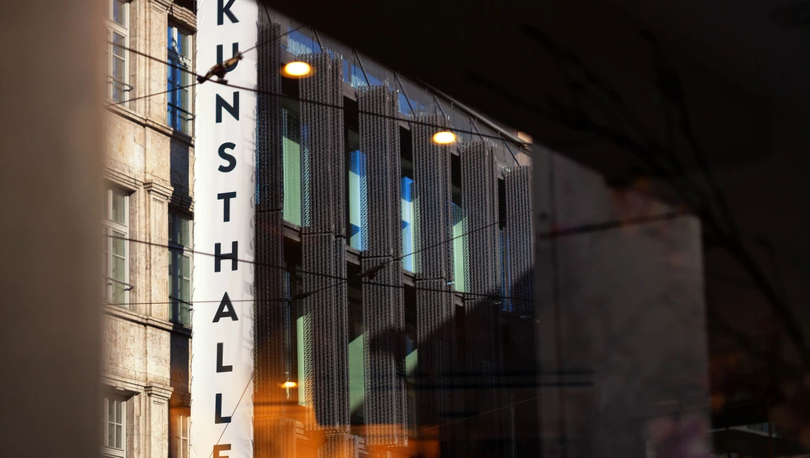 Ansicht einer Häuserzeile mit einem großem weißen Schild „KUNSTHALLE“ an einer Hausfassade und etwas verschwommenem Hintergrund.