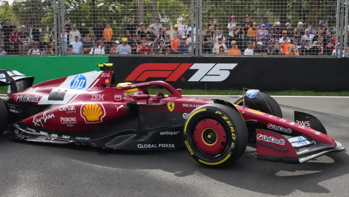 Formel-1-Rennwagen in Ferrari-Rot auf der Rennstrecke, umgeben von Sicherheitszäunen und Zuschauern. Auf dem Auto sind Sponsorenlogos wie Shell und HP sichtbar, im Hintergrund das F1-Logo mit der Zahl 75.